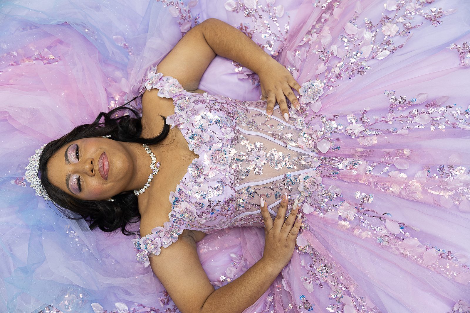 Quinceañera lying in her lavender gown, photographed from above